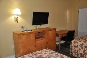 a hotel room with a desk and a television on a dresser at Best Rest Inn - Jacksonville in Jacksonville