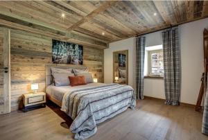 サン・ジェルヴェ・レ・バンにあるChalet de L'Ours Blancの木のアクセントの壁とベッドが備わるベッドルーム1室が備わります。