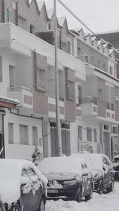 dois carros cobertos de neve em frente a um edifício em Appartement à louer à imouzzar kander em Imouzzer Kandar