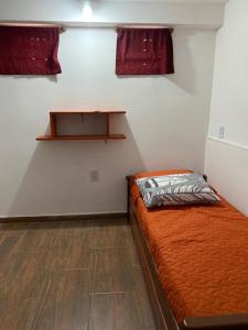 1 dormitorio con 1 cama con edredón de naranja en Departamento céntrico los cinco hermanos en Capilla del Monte