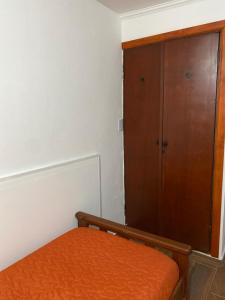 1 dormitorio con 1 cama y armario de madera en Departamento céntrico los cinco hermanos en Capilla del Monte