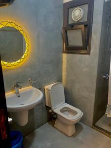 een badkamer met een wastafel, een toilet en een spiegel bij Portosaid بورتو سعيد (غرفه وصاله ) in `Ezbet Shalabi el-Rûdi