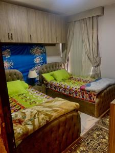two beds in a room with green sheets at Portosaid بورتو سعيد (غرفه وصاله ) in `Ezbet Shalabi el-Rûdi