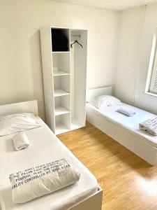 um pequeno quarto com 2 camas e um closet em Bus Station Hostel em Pristina