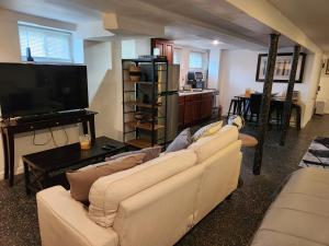 a living room with two couches and a flat screen tv at Cozy Studio; Lower Level Unit in Laurelton