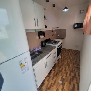 una piccola cucina con armadietti bianchi e pavimenti in legno di La Francisca a La Carolina