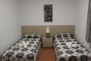 a bedroom with two beds and a lamp on a table at Villa Piscis in Cala Blanca