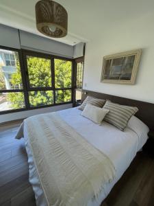 1 dormitorio con 1 cama blanca grande y ventanas en ALTOS COLÓN Vistas al mar EXCELENTE UBICACIÓN en Mar del Plata