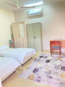 a room with two beds and a table and a rug at Reef Alhamra in Al Ḩamrāʼ