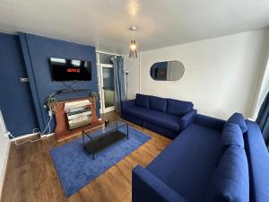 a living room with a blue couch and a tv at Lovely Spacious 3 bedrooms house in Kingshurst