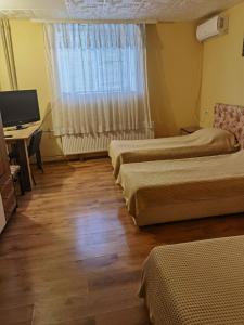a room with two beds and a desk and a television at House for Guests and Friends in Svishtov