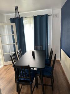 a dining room table and chairs with blue curtains at Lovely Spacious 3 bedrooms house in Kingshurst