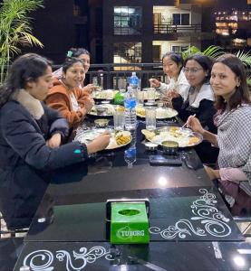 un grupo de personas sentadas alrededor de una mesa comiendo comida en Hotel Pokhara Paradise, en Pokhara