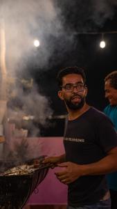 un hombre sosteniendo una sartén de comida con humo en Amayour Surf Hostel, en Taghazout