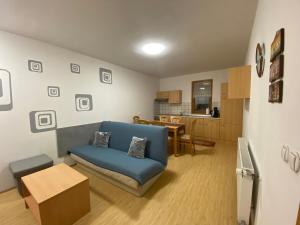 a living room with a blue couch and a kitchen at APARTMA BRDO BC in Bovec