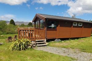 a large wooden cabin with a porch in a field at Great Escapes,Rhinog mountain View in Trawsfynydd