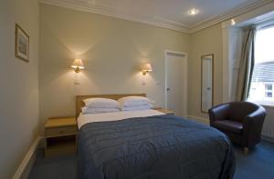 a hotel room with a bed and a chair at St Clair Hotel in Thurso