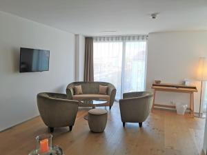 a living room with chairs and a couch and a tv at Hotel AVA in Sempach Station