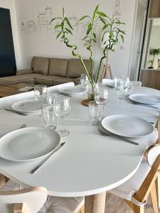 una mesa blanca con platos y copas de vino. en Le Prieuré, en La Rochelle