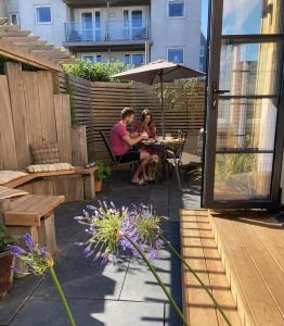 zwei Personen, die an einem Tisch unter einem Schirm sitzen in der Unterkunft Summer Breeze in Newquay