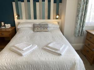 Un dormitorio con una cama blanca con toallas. en Summer Breeze, en Newquay