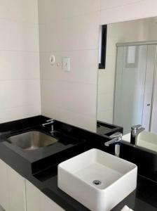 Baño en blanco y negro con lavabo y espejo en Estúdio Completo com Linda Vista no Ed. Vertigo, en Campo Grande