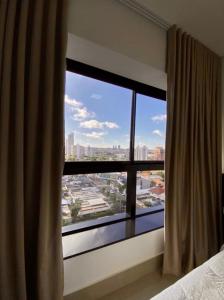 een slaapkamer met een groot raam met uitzicht op de stad bij Estúdio Completo com Linda Vista no Ed. Vertigo in Campo Grande
