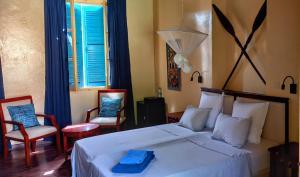 1 dormitorio con 1 cama blanca y 2 sillas en La Maison du Marin, en Gorée