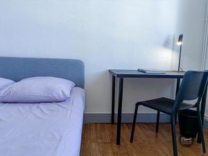1 dormitorio con escritorio, 1 cama y 1 silla en Appartement calme lumineux proche gare 3 chambres, en Angulema