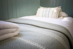 un letto con lenzuola bianche e un cuscino sopra di The Showman's Waggon a Hexham