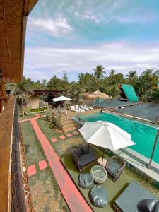 a swimming pool with an umbrella and chairs next to it at Glamping Alona in Panglao