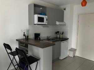 a kitchen with a counter and chairs and a microwave at STUDIO BORDEAUX in Bordeaux