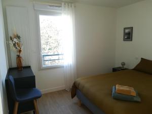 a bedroom with a bed and a chair and a window at Charmant T2 proche Gare in Laval
