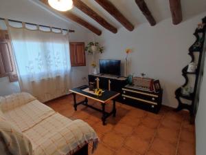 sala de estar con sofá, mesa y TV en Casa Rural Cortijo la Jimena, en Caravaca de la Cruz