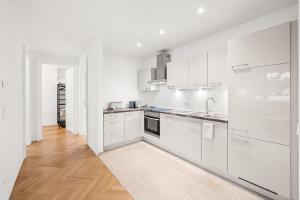 cocina blanca con armarios blancos y suelo de madera en Vienna Chic Residences #Suite 15, en Viena
