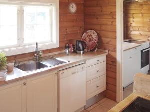 TjørneholmにあるHoliday home Nykøbing Sj IIの木製の壁とシンク付きのキッチン、窓が備わります。