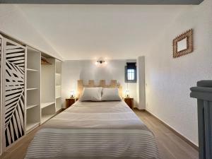 una camera da letto con un grande letto e pareti bianche di Appartement Duplex 4pers Climatisé - Location Valadié Camargue a Saintes-Maries-de-la-Mer