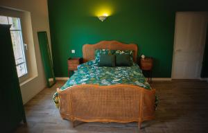a bedroom with a large bed with a green wall at Mas de la Roule, 4 studios, piscine chauffée, studio SPA, parc 2 ha, Pont d'Avignon à pied in Avignon