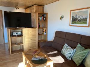 ein Wohnzimmer mit einem Sofa und einem Flachbild-TV in der Unterkunft Alpenflair Ferienwohnung 102 Frohnatur in Oberstdorf