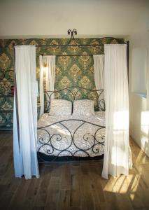 a bedroom with a bed with a ornate headboard and curtains at Mas de la Roule, 4 studios, piscine chauffée, studio SPA, parc 2 ha, Pont d'Avignon à pied in Avignon