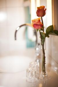 Eine Vase mit einer Rose auf dem Tisch. in der Unterkunft Business & Art Hotel Markgraf in Emmendingen