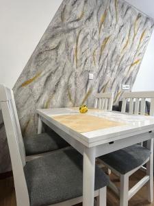 einen weißen Tisch und zwei Stühle vor einer Wand in der Unterkunft D-moll Divcibare in Divčibare