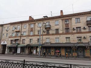 a large brick building with people walking on a street at Soborna Apartment in Rivne