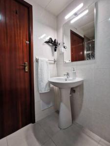 een witte badkamer met een wastafel en een spiegel bij Alegria A in Funchal
