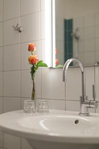 a bathroom sink with a vase with a flower in it at Business & Art Hotel Markgraf in Emmendingen