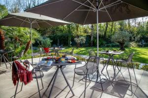 due tavoli e sedie sotto ombrelloni su un patio di Park Hotel Sabina a Magliano Sabina
