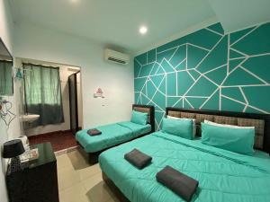 een slaapkamer met 2 bedden en een blauwe muur bij MJ inn in Ranau