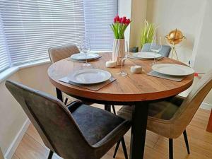 a wooden table with chairs and plates and wine glasses at Rosa House in Darlington