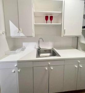 a kitchen with white cabinets and a sink and two wine glasses at The Love Nest at Central Athens Kolonaki in Athens