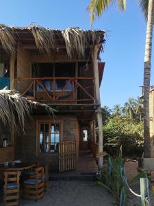 ein Resortgebäude mit einer Veranda, einem Tisch und Stühlen in der Unterkunft Palmarío Hostal in Guachaca